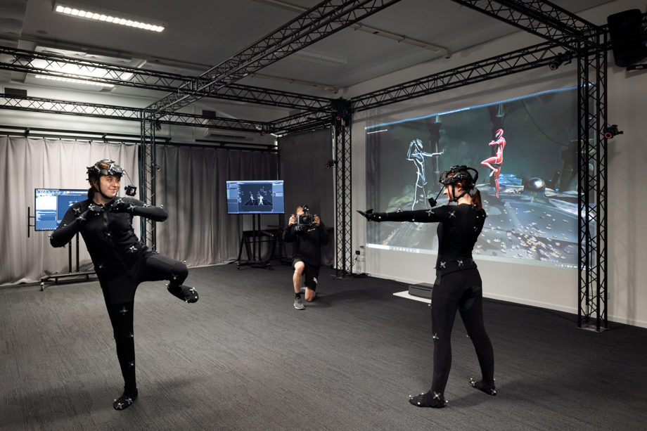 MOCAP studio in action Students active in MOCAP suits in front of project screen with roaming camera